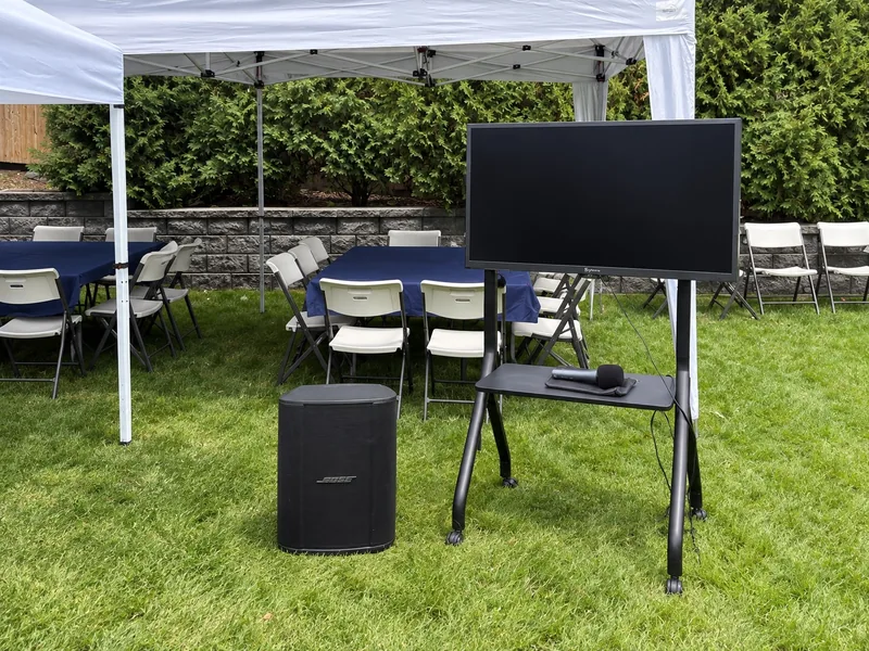 Bongo TV, stand, speaker, and microphone arranged beside the backyard tents